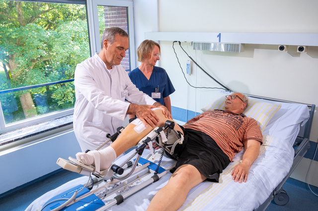 Zwei Mitarbeiter unterstützen einen Patienten